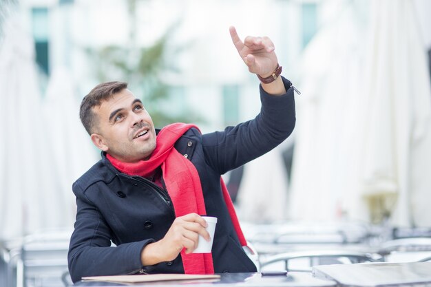 Happy young man making order in sidewalk cafe