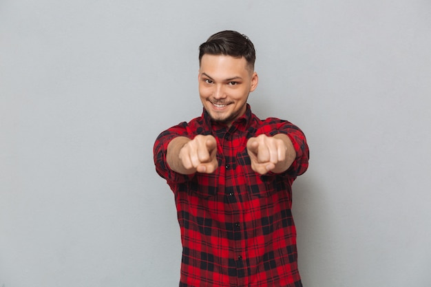 Happy young man pointing. Looking at camera.