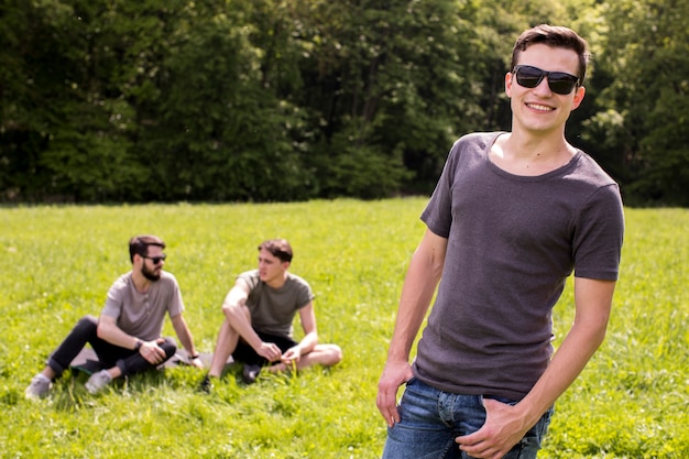 Free photo happy young man posing on meadow with friends