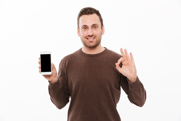 Счастливый молодой человек, показывая дисплей мобильного телефона