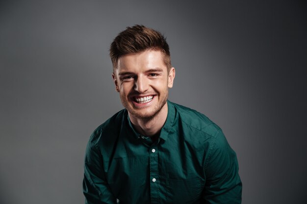 Free photo happy young man sitting isolated over grey