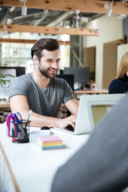 オフィスのコワーキングに座って幸せな若い男