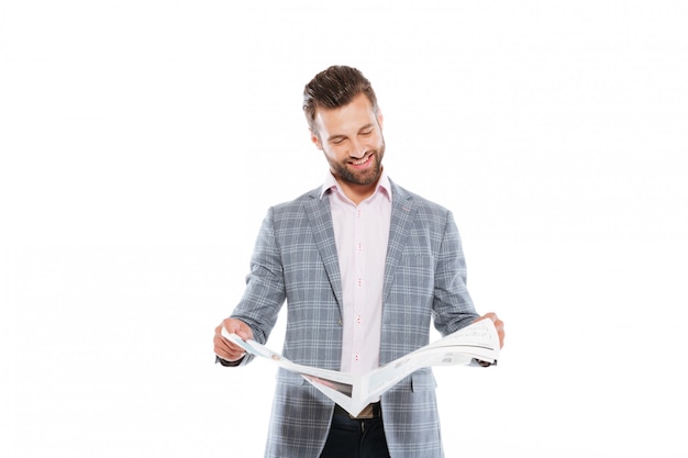 Happy young man standing isolated reading gazette