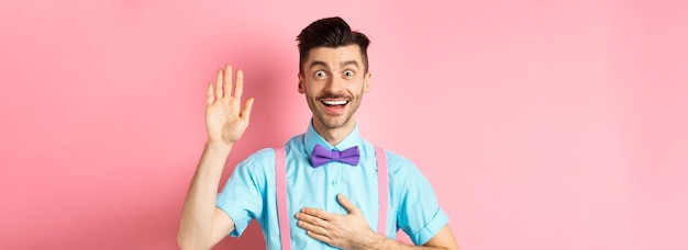 Free photo happy young man telling truth making promise holding hand on heart and arm raised swearing to be hon