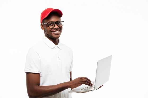 Happy young man wearing cap using laptop computer