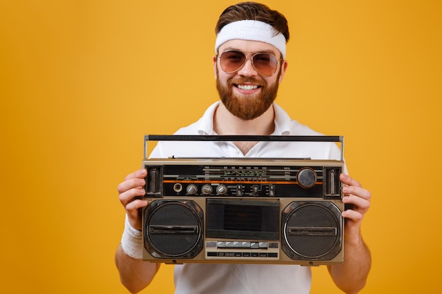 Happy young man wearing sunglasses holding tape recorder