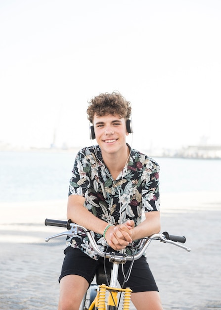 Free photo happy young man with bicycle listening to music on headphone