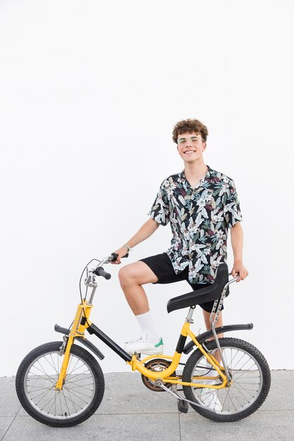 Happy young man with bicycle standing on sidewalk