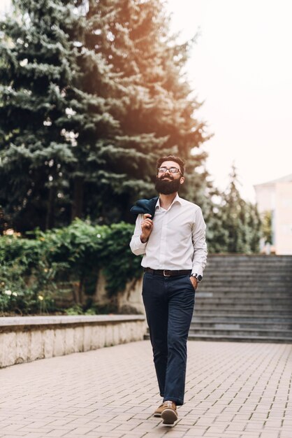 Happy young man with hands in his pockets walking in the park