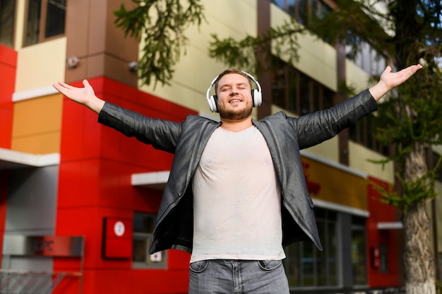 Free photo happy young man with headphones raising his hands in sides