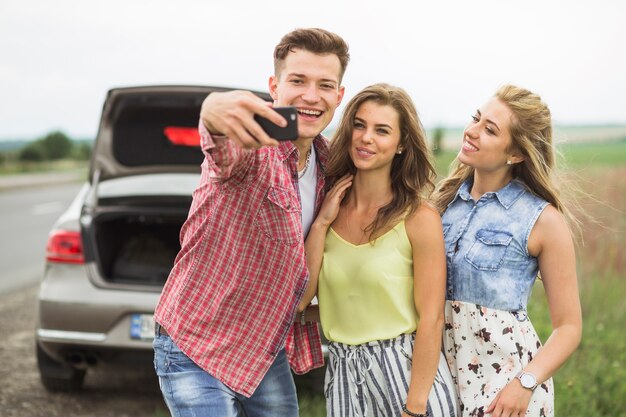 Happy young man with his friends taking self portrait through mobile phone