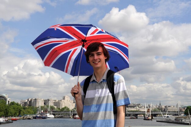 런던에서 우산을 가진 행복 한 젊은이