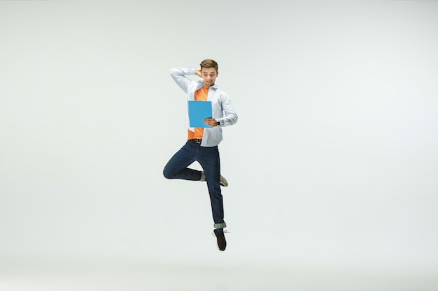 Happy young man working at office, jumping and dancing in casual clothes or suit isolated on white  background.