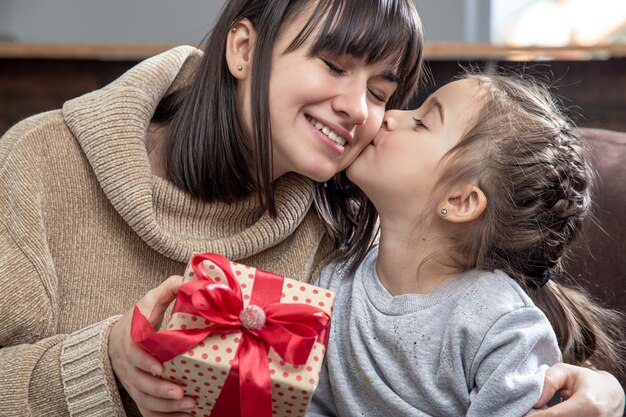 Happy young mom with her cute daughter. The concept of congratulations on the holiday, family relationships and quality time together.