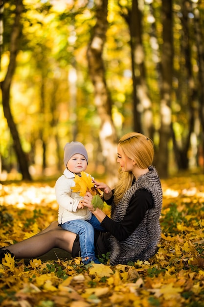 Felice giovane madre e suo figlio piccolo trascorrere del tempo nel parco in autunno.