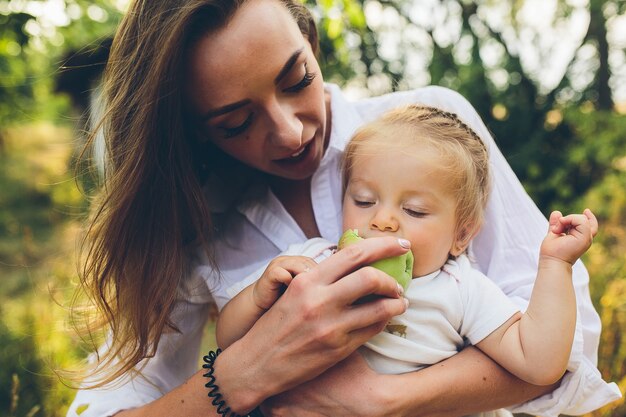 Happy young mother and lovely daughter holding apple