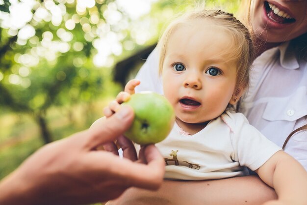 Happy young mother and lovely daughter holding apple