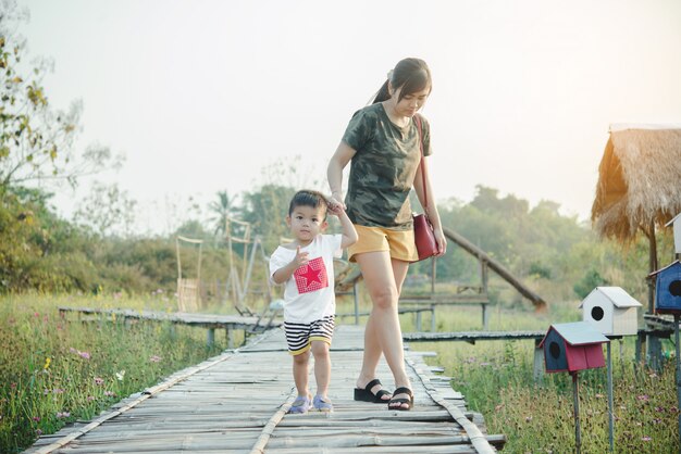 Счастливая молодая мать играть и веселиться с маленьким сыном в парке в солнечный летний день