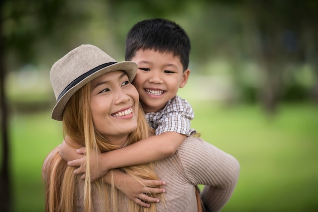 Happy young mother and son laughing little boy getting a piggyback ride on her back.