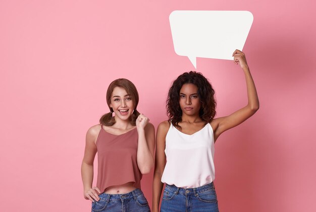 Happy young multiethnic couple woman holding empty speech bubble isolated on pink studio background