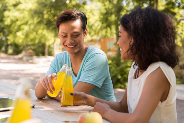 Happy young multiethnic friends students outdoors drinking juice