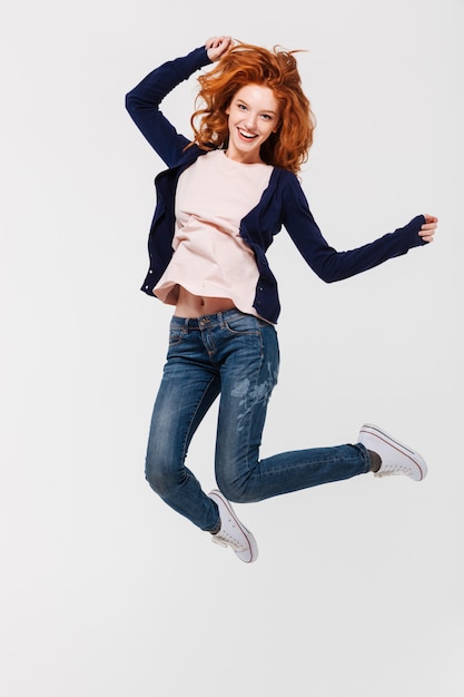 Happy young redhead lady jumping