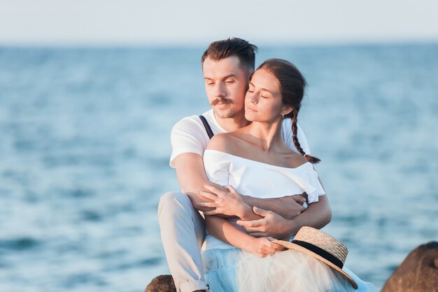 Счастливая молодая романтическая пара отдыхает на пляже и смотрит на закат