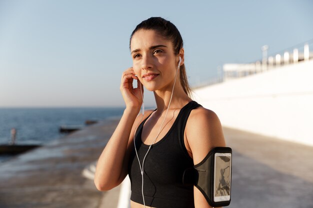 Happy young sports woman listening music outdoors.