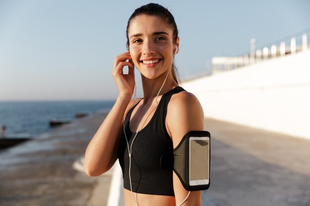 Happy young sports woman listening music outdoors.