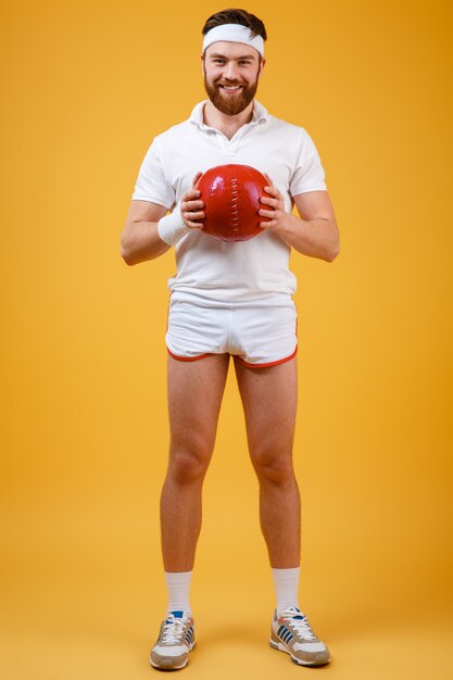 Happy young sportsman holding ball. Looking at camera.