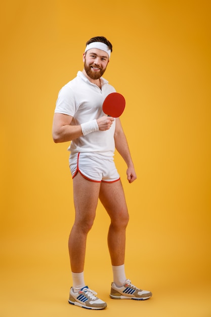 Счастливый молодой спортсмен, держа ракетку для настольного тенниса.
