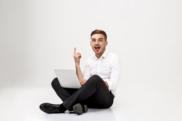 Happy young successful businessman sitting with laptop.