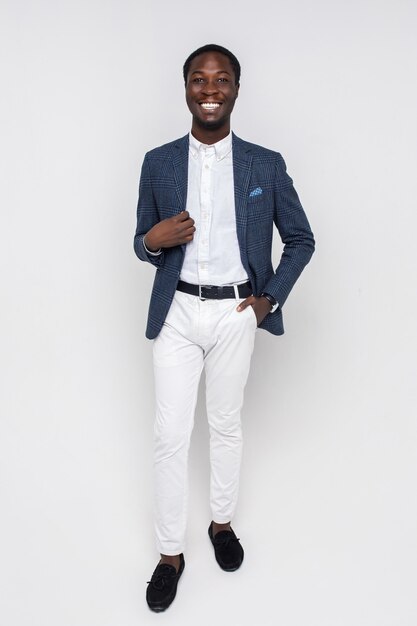 Happy young successful man in business stylish clothes standing on isolated white wall