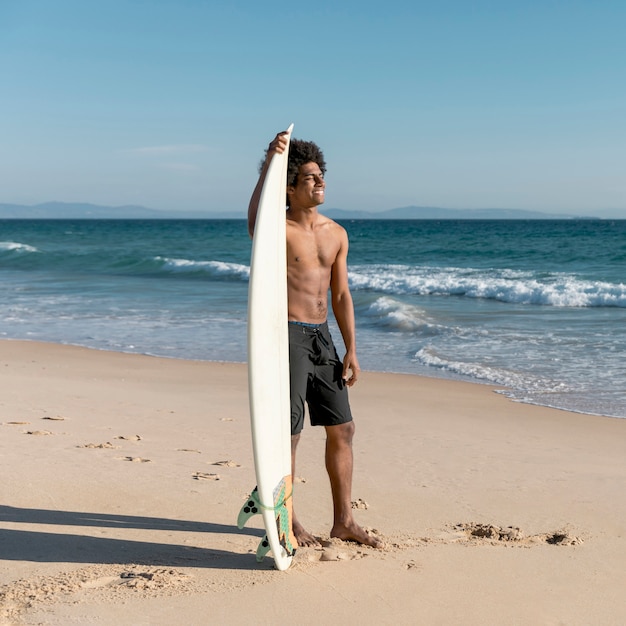 Foto gratuita felice giovane surfista guardando il mare blu