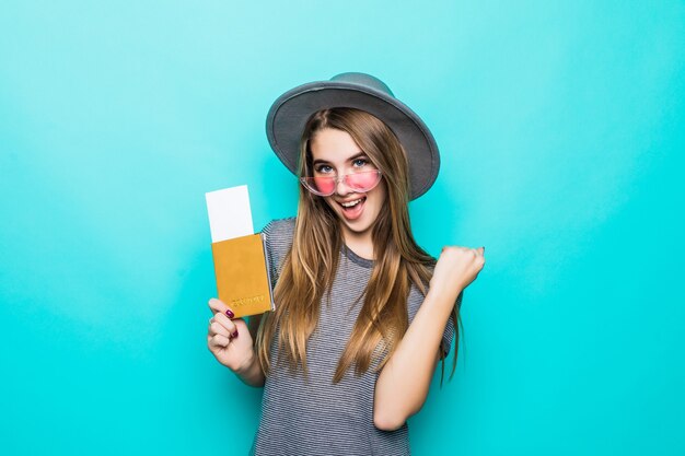 Happy young teenage lady holds her passport documents with ticket in her hands isolated on green studio wall