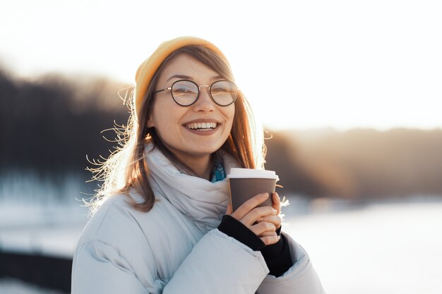 テイクアウトコーヒーカップを保持している幸せな若い10代女性