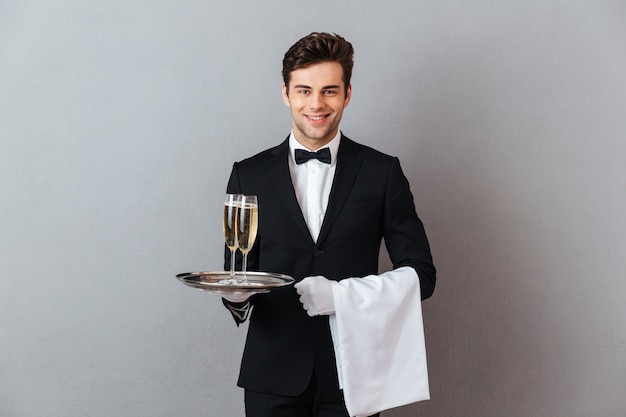 Free photo happy young waiter holding glass of champagne and towel.