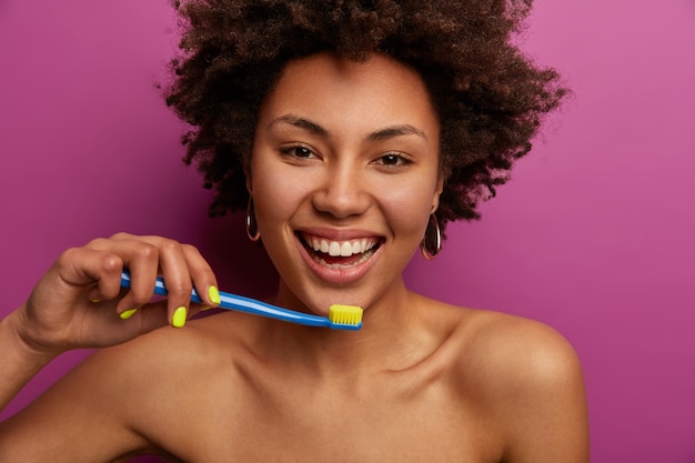 Happy young woman brushes teeth, has brilliant smile