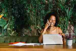 Free photo happy young woman closing the laptop while talking on cellphone