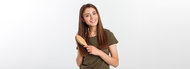 Happy young woman combing her long healthy hair on white background