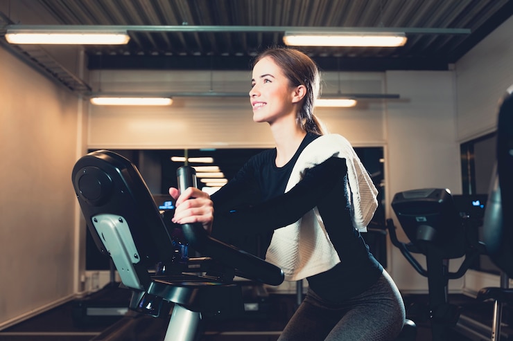 Free Photo happy young woman cycling in gym