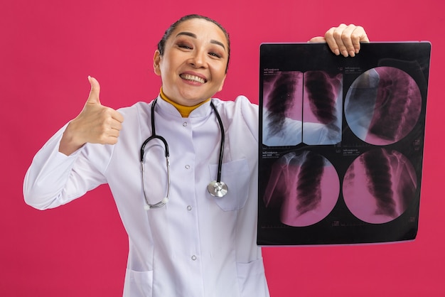 엄지 손가락을 보여주는 미소 폐의 엑스레이를 들고 행복 한 젊은 여자 의사