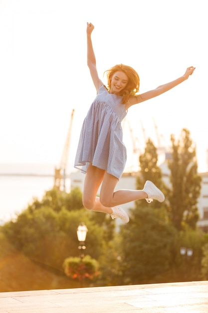 드레스 점프 야외에서 행복 한 젊은 여자
