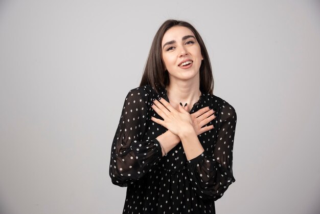 Happy young woman in dress putting hands on her chest.