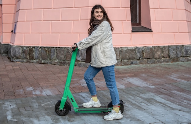 Foto gratuita felice giovane donna su scooter elettrico in città.