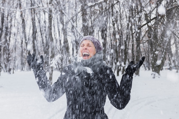 Счастливая молодая женщина, наслаждаясь снегопад в зимнем лесу