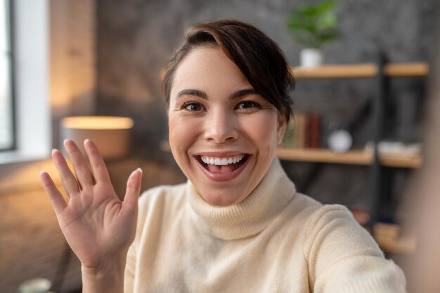 Happy young woman greeting someone via Skype