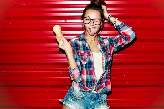 Happy young woman having fun and showing her tongue on red background