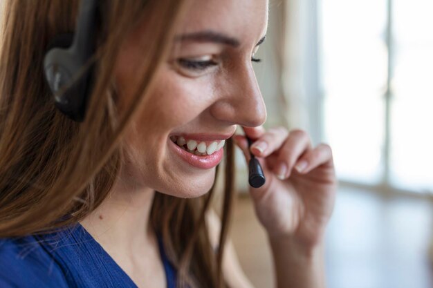 ヘッドフォンで話す幸せな若い女性がノートパソコンを見てメモをとるビジネス電話会議で話すウェブカメラによる会議オンライントレーニングecoachingコンセプト