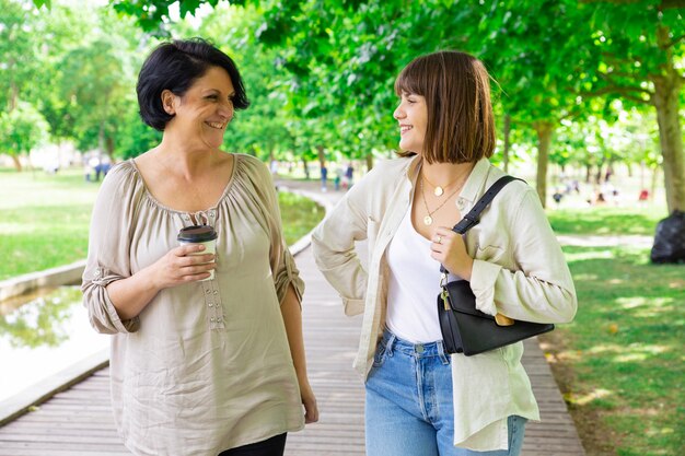 행복 한 젊은 여자와 그녀의 어머니 채팅 및 공원에서 산책
